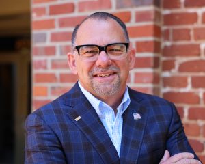 Financial advisor in professional attire with American flag pin, ready to serve clients in Aiken and Lexington wealth.