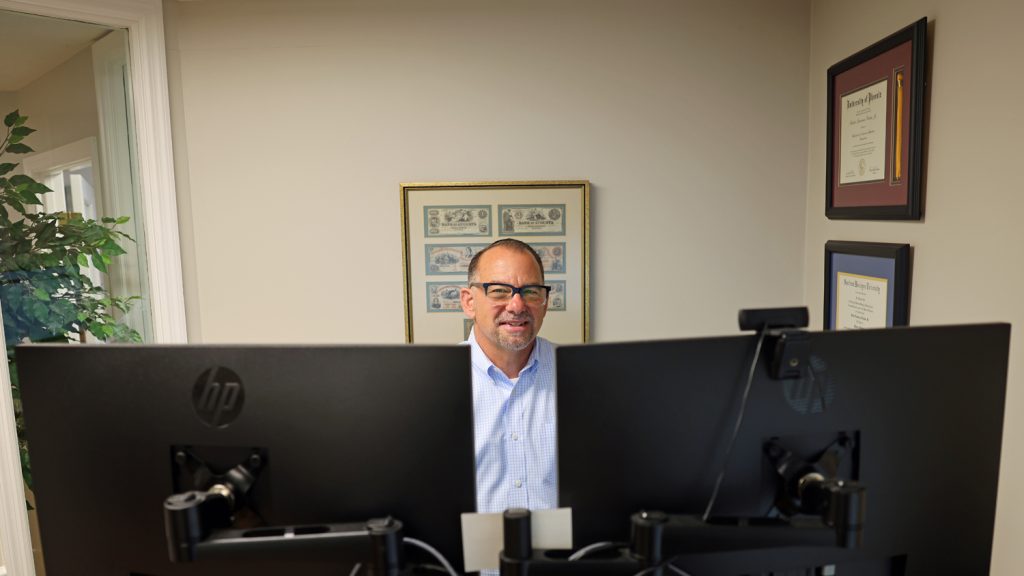 Financial advisor at desk with dual monitors in professional office, ready to assist with wealth management and financial.
