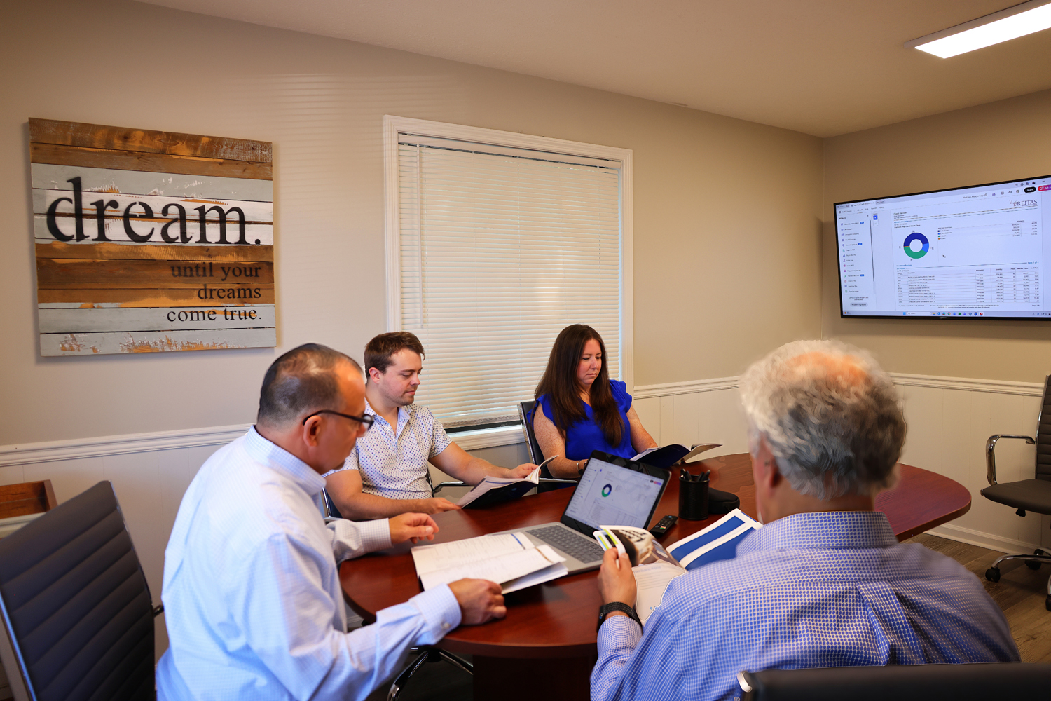 Financial advisors and clients collaborate around a conference table to review wealth management and investment planning.